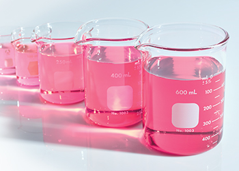 Una hilera de vasos de precipitación llenos de líquido rosado