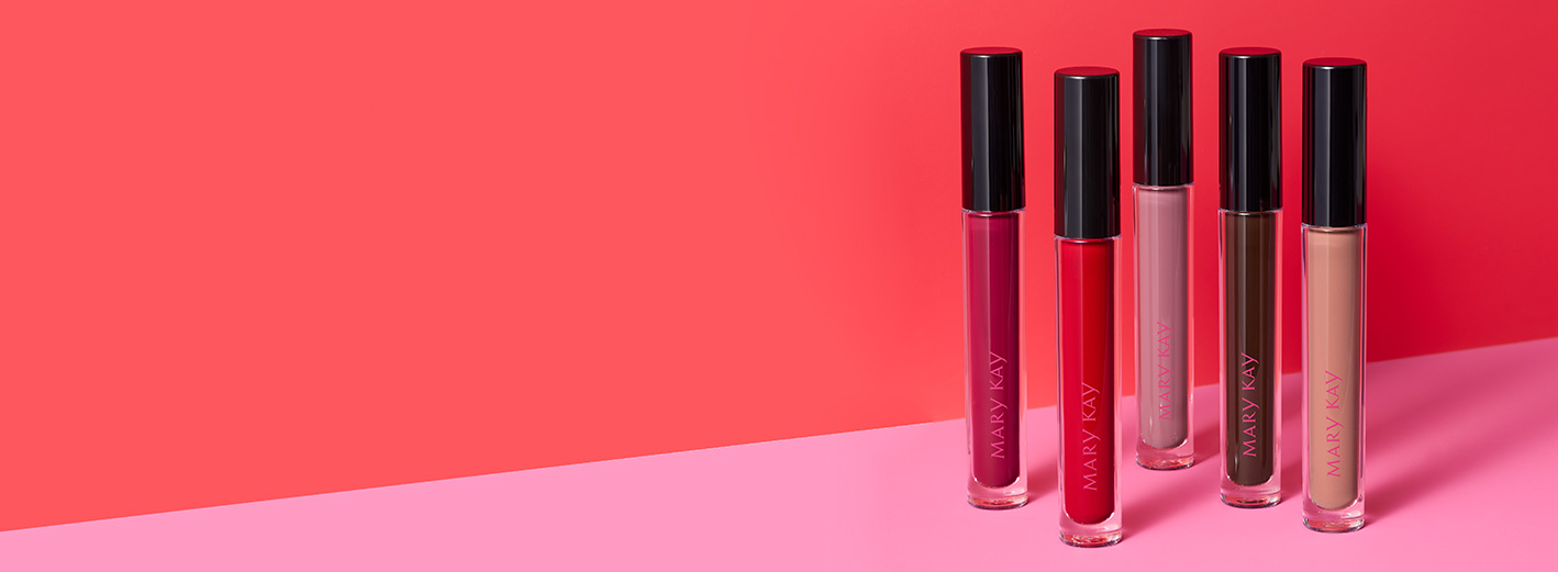 Tubos del nuevo Mary Kay® Matte Liquid Lipstick de edición especial contra un fondo rojo y rosa