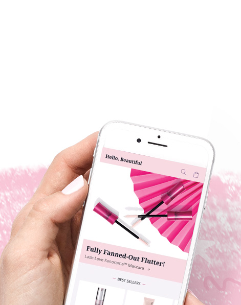 Imagen de unas manos que sostienen un teléfono inteligente en el que se muestra la aplicación Mary Kay®, todo contra un fondo de color rosa 