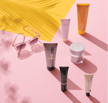 Imagen de varios productos del cuidado de la piel y cuerpo Mary Kay® con FPS y unas gafas de sol contra un fondo de color rosa y amarillo 