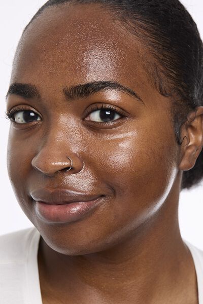 Person gently touching their face, showcasing smooth, hydrated, glass-like skin with a radiant glow.