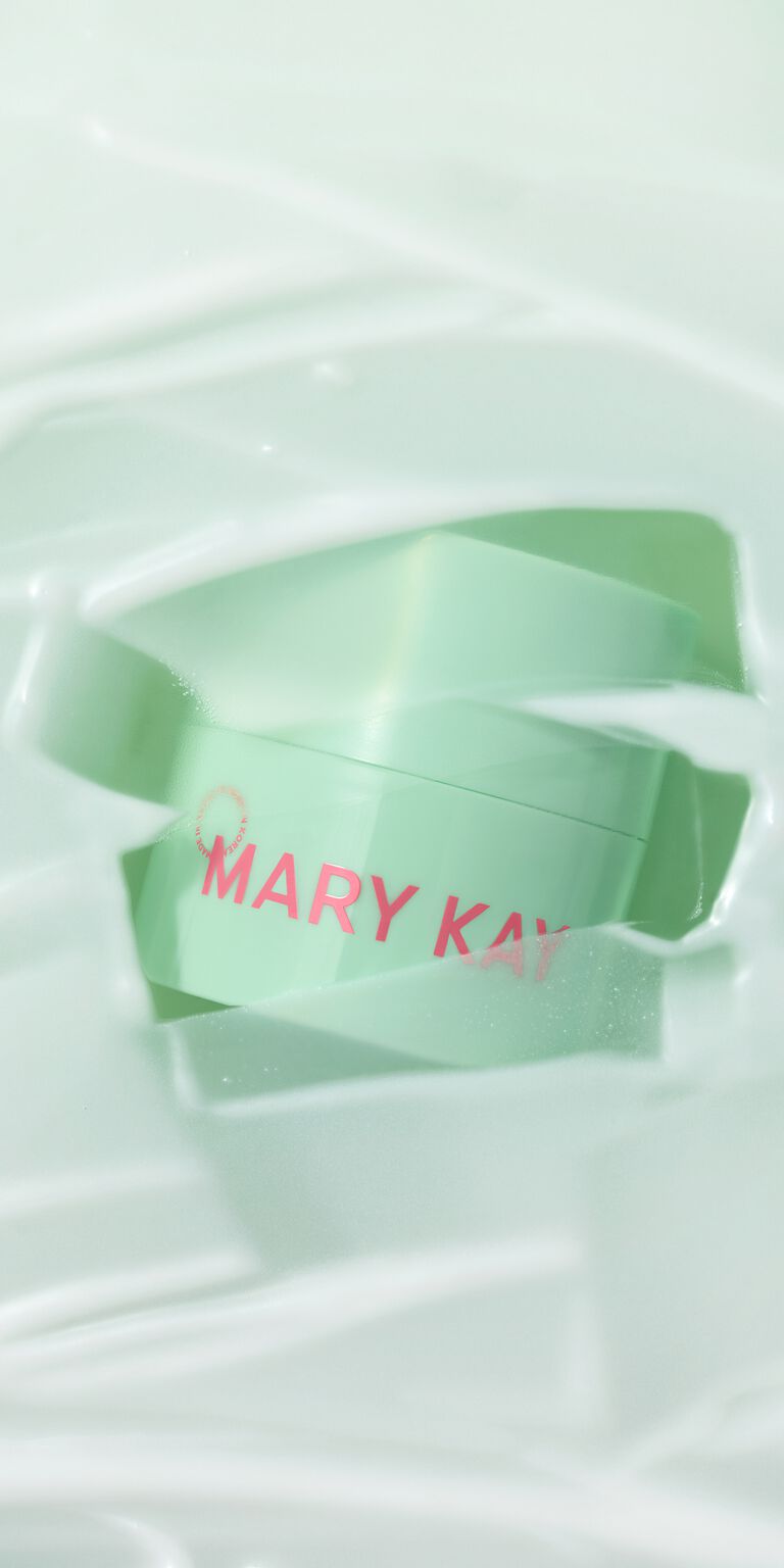 Frasco verde del Melt-In Cleansing Balm asom&aacute;ndose entre im&aacute;genes del producto