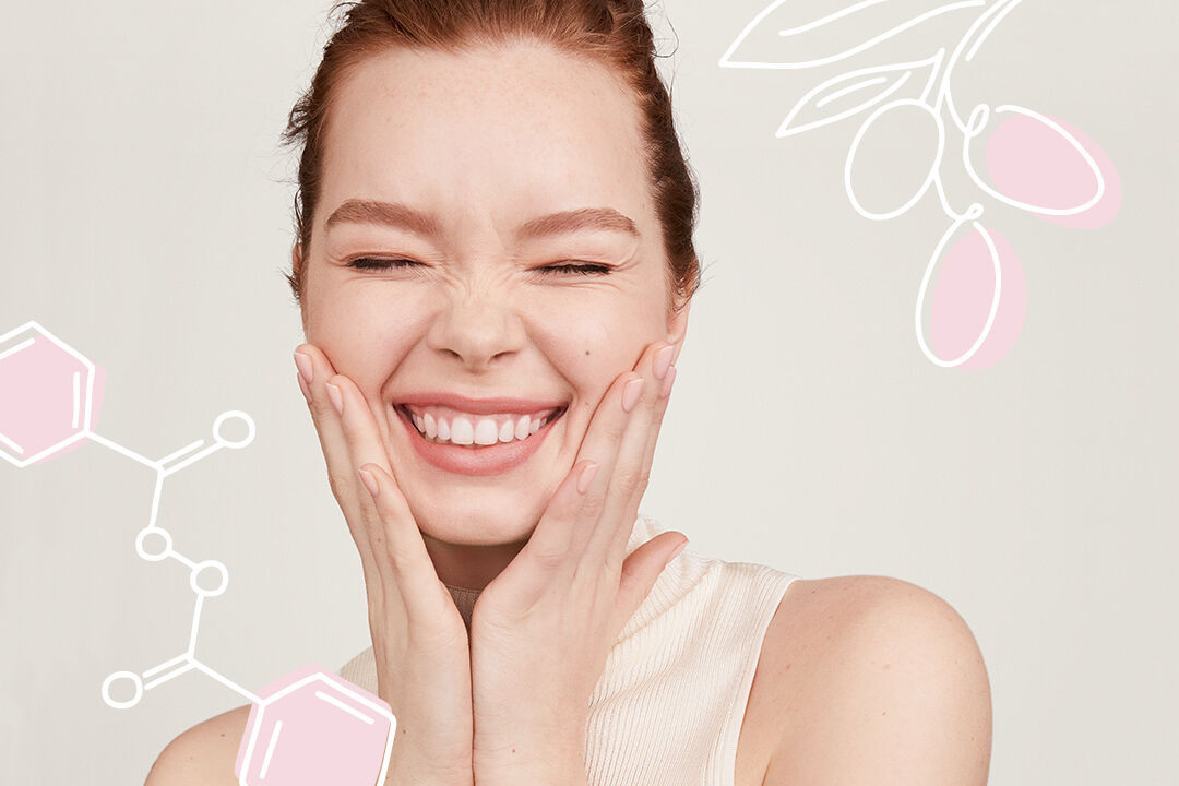 Mujer sonriendo con las manos junto a las mejillas. Al fondo, ilustraciones de los ingredientes activos de Mary Kay.