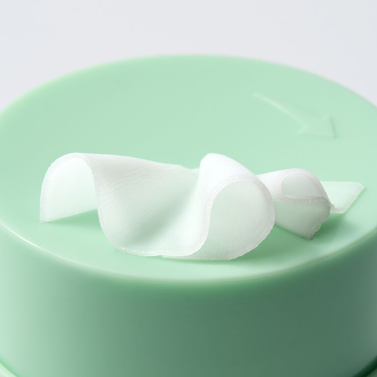 Close-up of white cleansing balm coming out of top of green jar