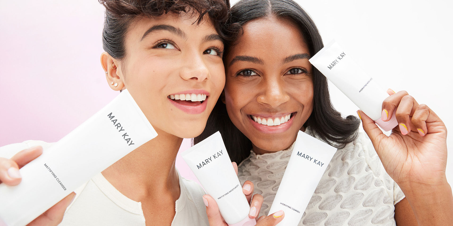 Dos modelos casta&ntilde;as sosteniendo productos del r&eacute;gimen del cuidado de la piel Mary Kay y sonr&iacute;en