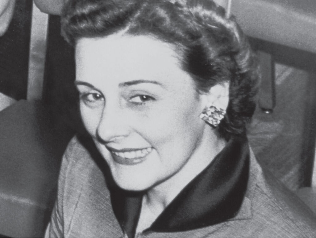 Fotografía antigua de la fundadora de Mary Kay luciendo un elegante traje y llamativos pendientes.