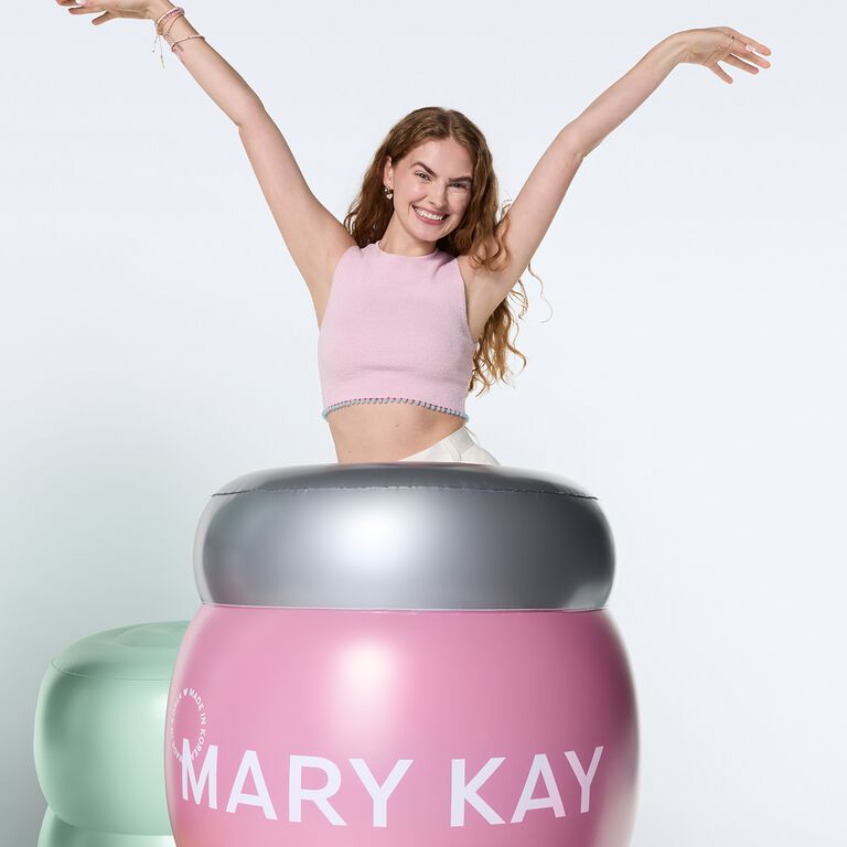 Mujer celebrando detr&aacute;s de un frasco gigante de Mary Kay Collagen Moisturizing gel.