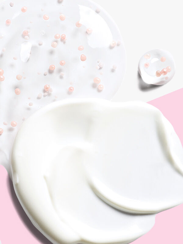 Un toque de crema de d&iacute;a del "Set Milagroso" de Mary Kay (TimeWise Daytime Defender FPS 30) y un toque de suero de noche (TimeWise Nighttime Recovery) sobre un fondo rosa y blanco.