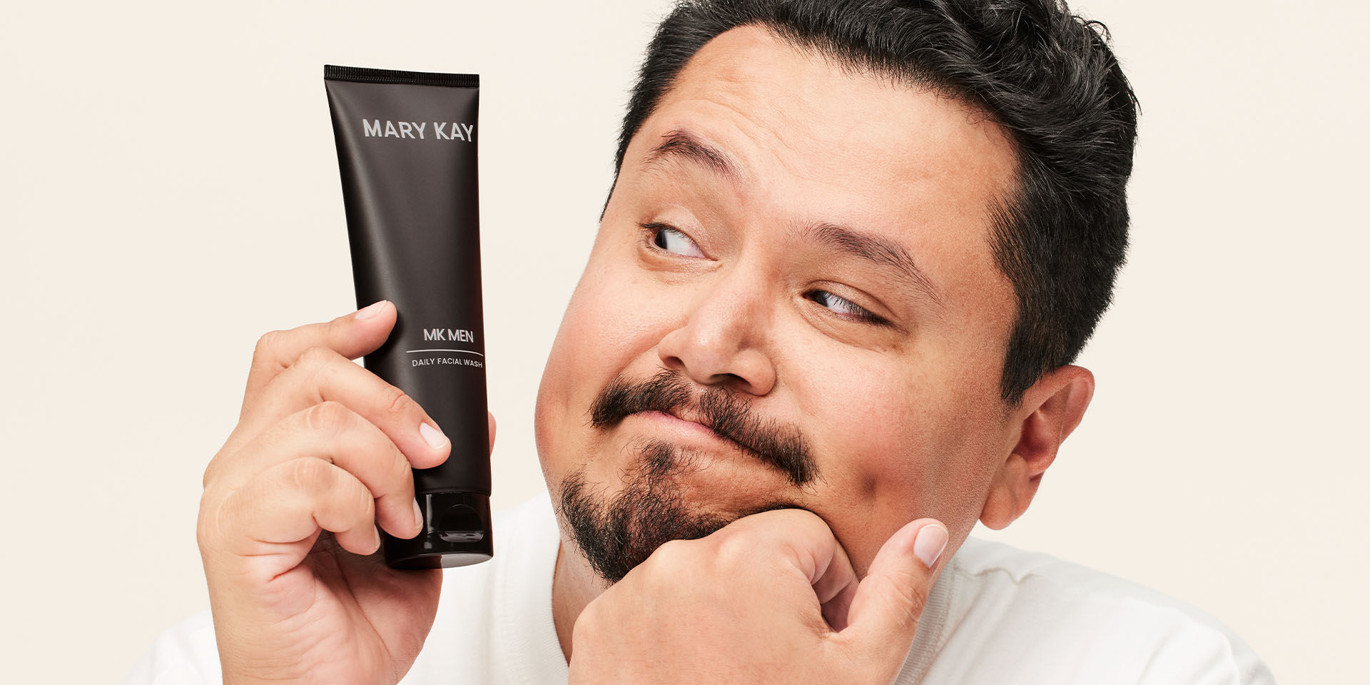 Modelo masculino sosteniendo el tubo del MKMens daily facial wash cerca de su rostro