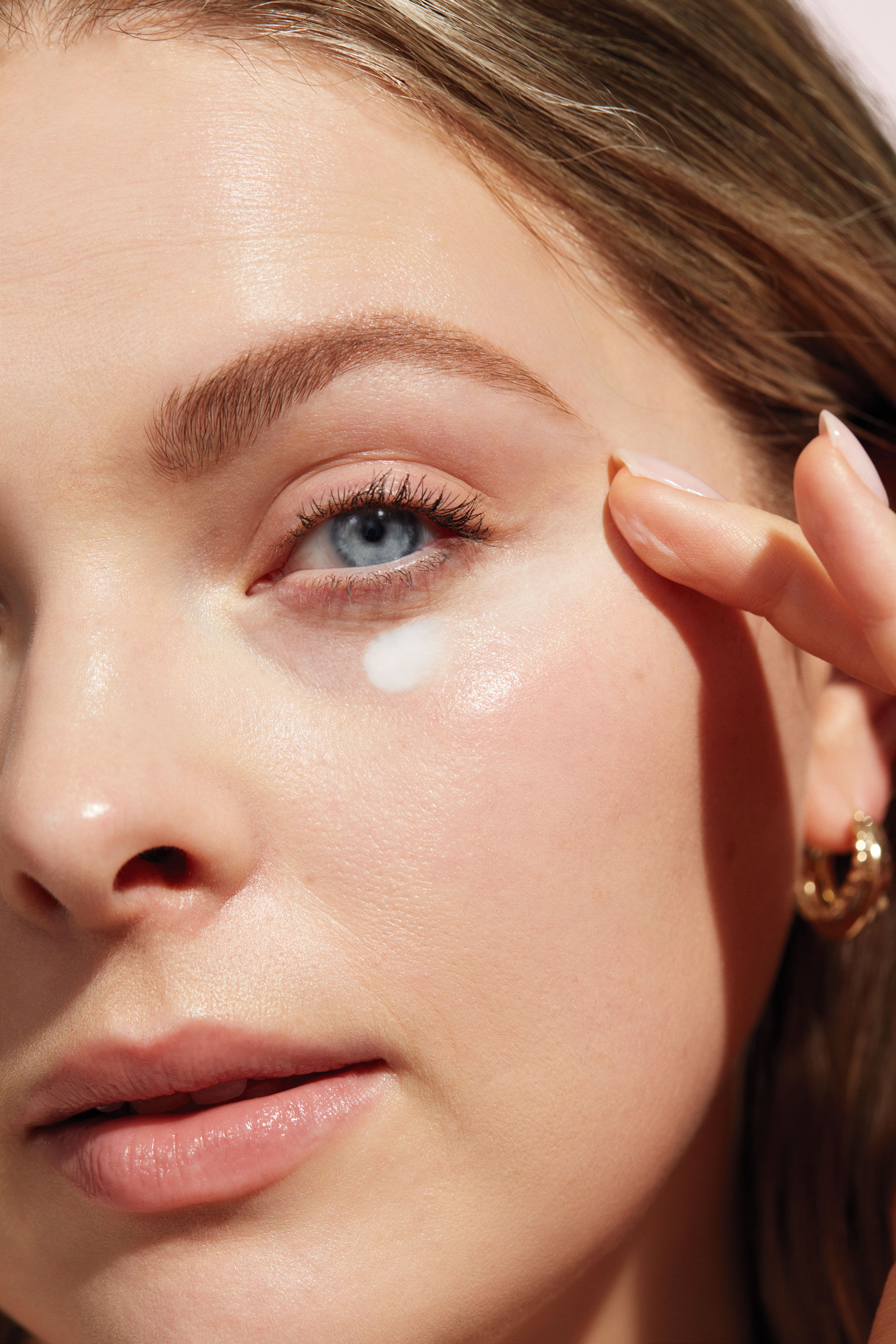 Primer plano del rostro de una mujer aplicando la crema para ojos Mary Kay con los dedos.