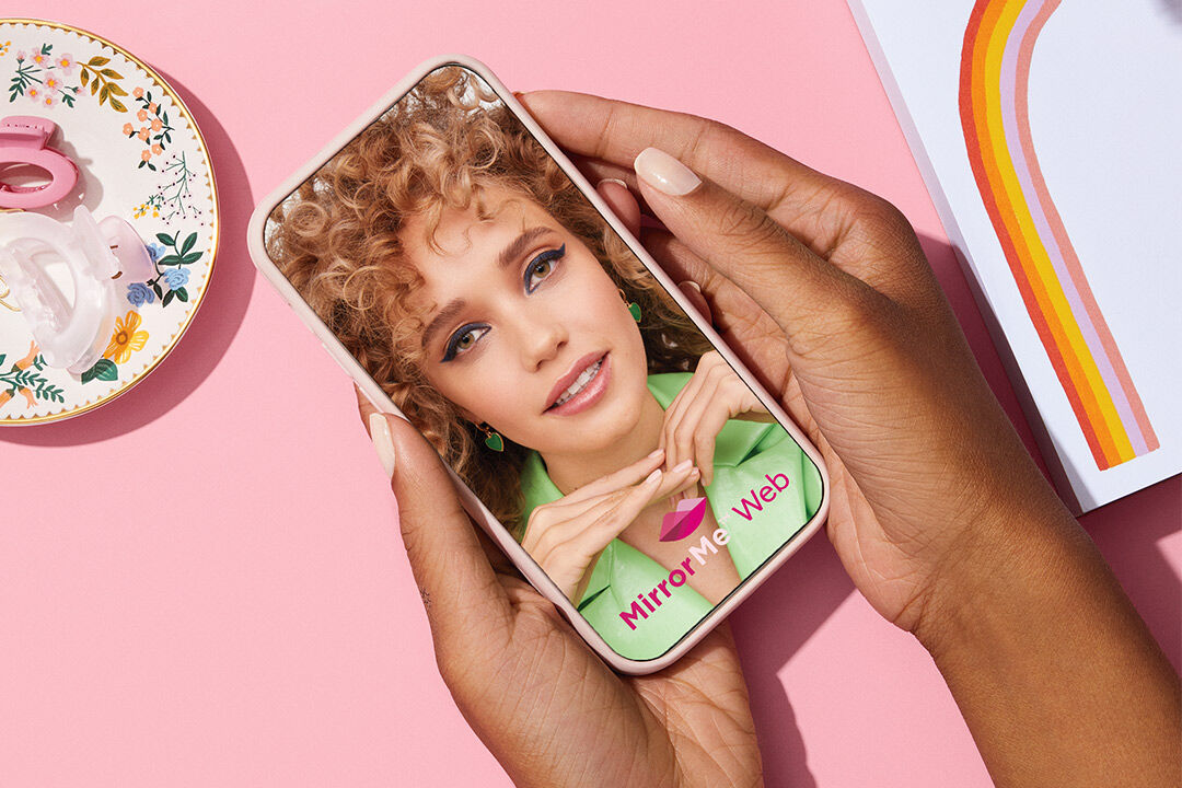 Mano sosteniendo un tel&eacute;fono que muestra la prueba virtual web de Mary Kay MirrorMe