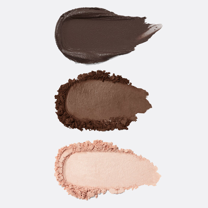 Product rubs of the pomade, powder and highlighter included in the limited-edition Mary Kay Brow Kit in Dark Brunette against plain background