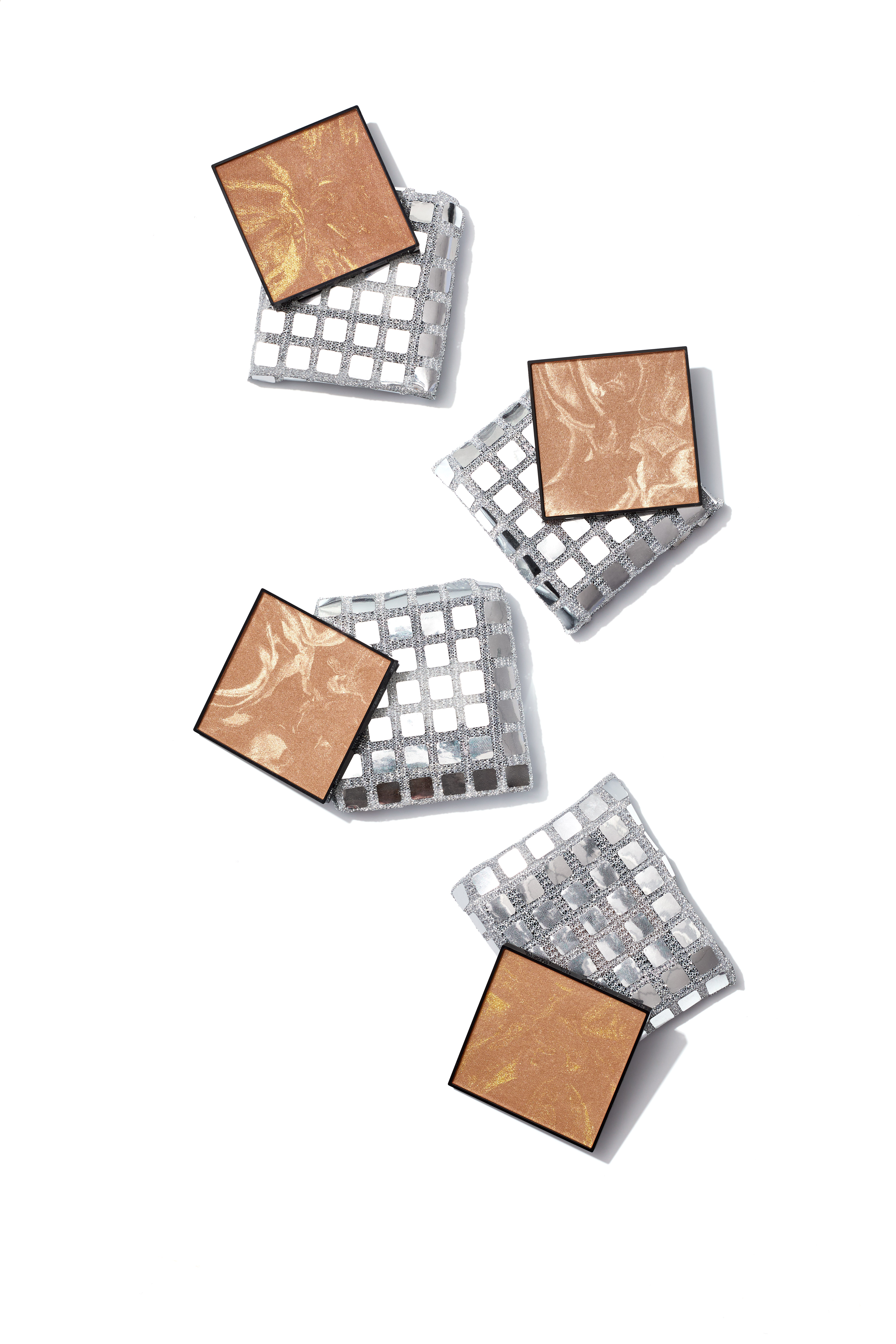 Close-up of two bronzer palettes resting on a reflective silver grid surface 