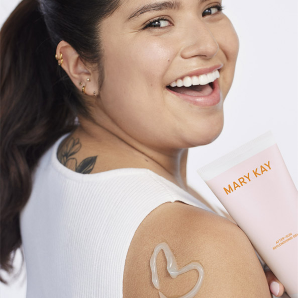 Smiling model with a heart on her shoulder holding a pink tube of Mary Kay After Sun Replenishing Gel