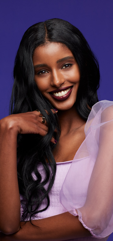 Mujer sonriendo a la c&aacute;mara con un labial hidratante Mary Kay Supreme en un tono intenso.