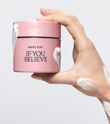 Hand holding a pink Mary Kay If You Believe Body Souffl&eacute; jar with body cream applied around the container and on the hand.